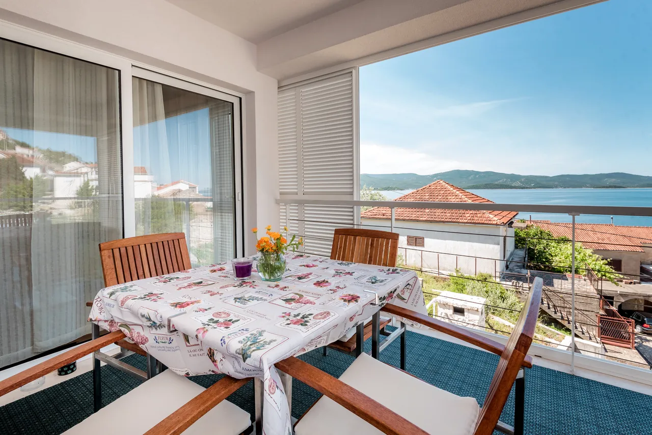 Überdachter Balkon mit Esstisch und Meerblick