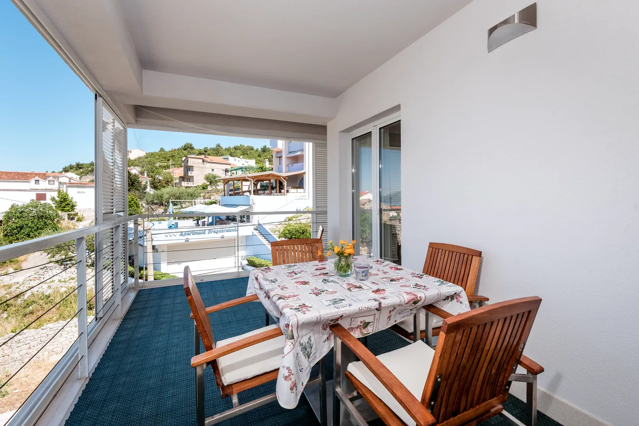 Überdachter Balkon mit Esstisch und Stühlen