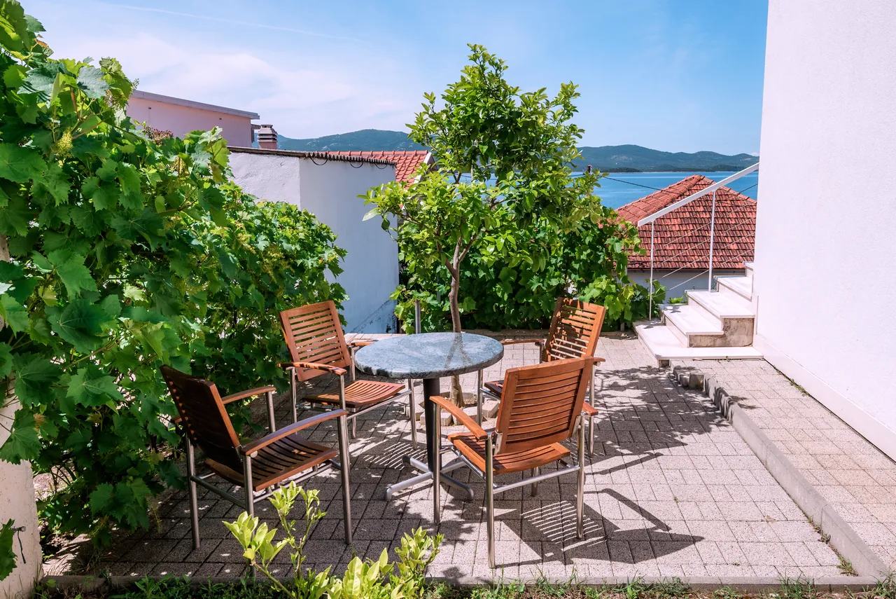 Gartenterrasse im Schatten einer Weinrebe mit Meerblick